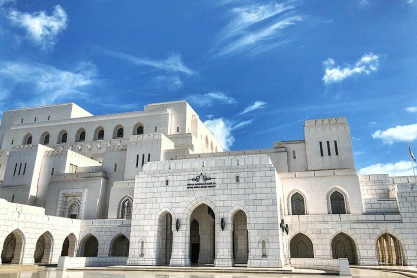 A large white building with multiple arches and a clear blue sky. 2