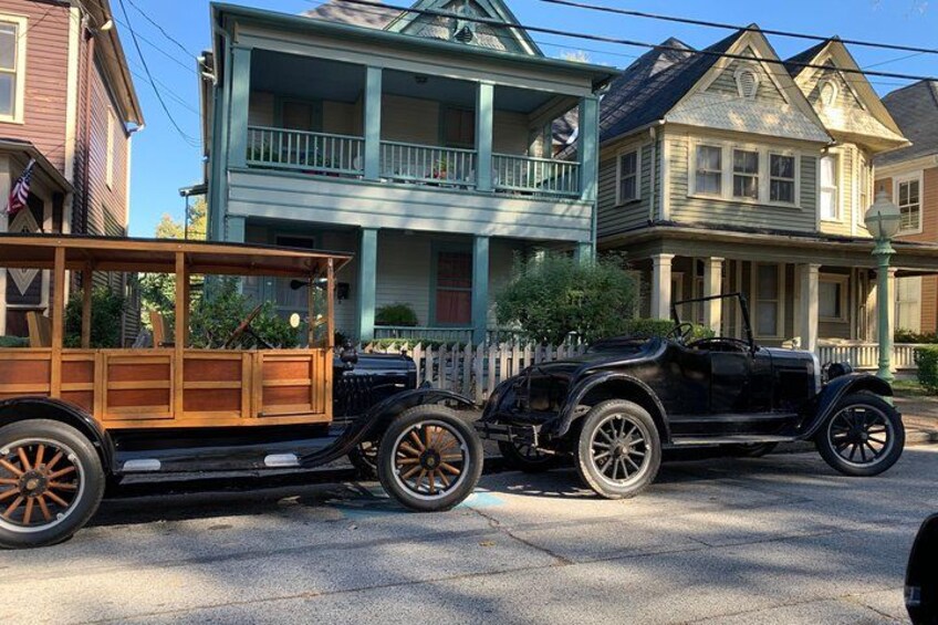 A vintage car towing a wooden trailer on a residential street. 4
