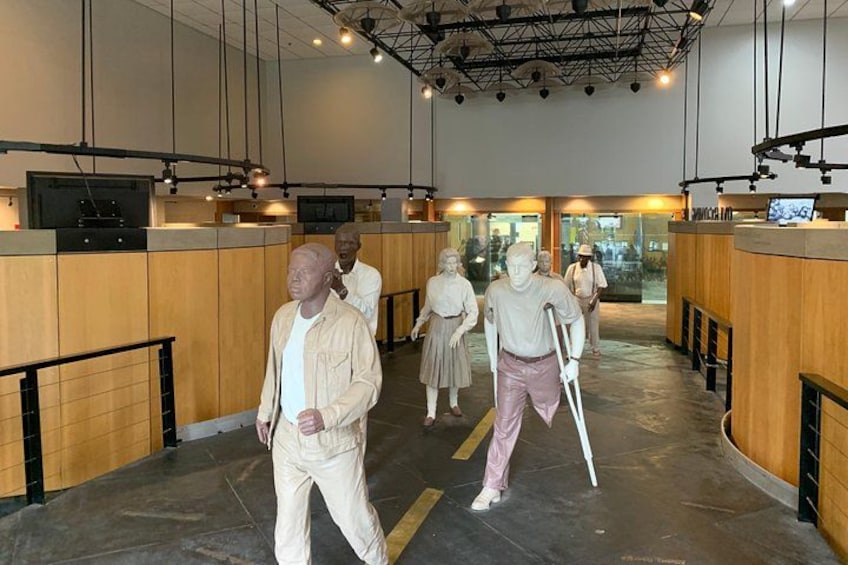 A museum interior with wooden paneling, a central walkway, and a few visitors. 3