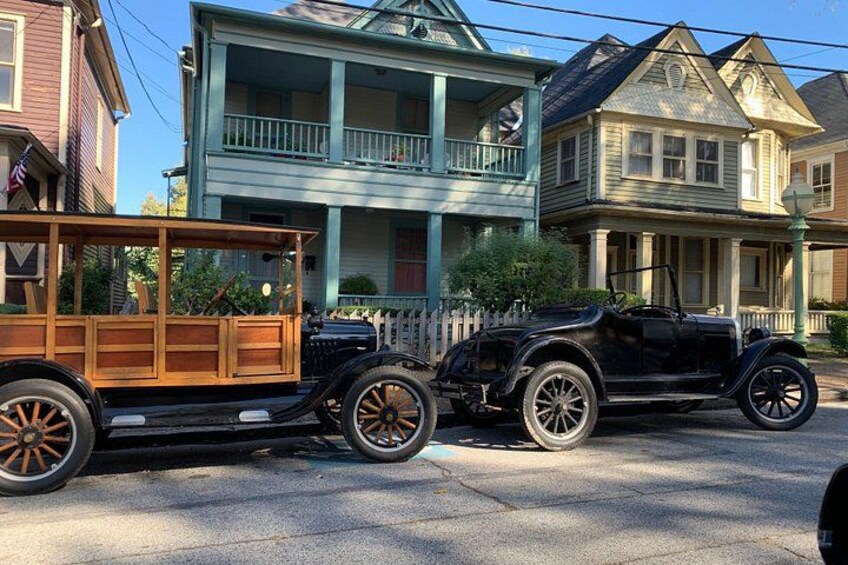 A vintage car towing a wooden trailer on a residential street. 4