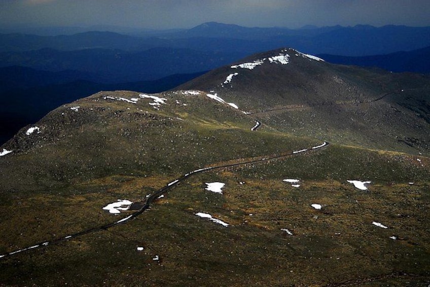 Un paysage de montagne avec une route sinueuse et des zones recouvertes de neige. 4