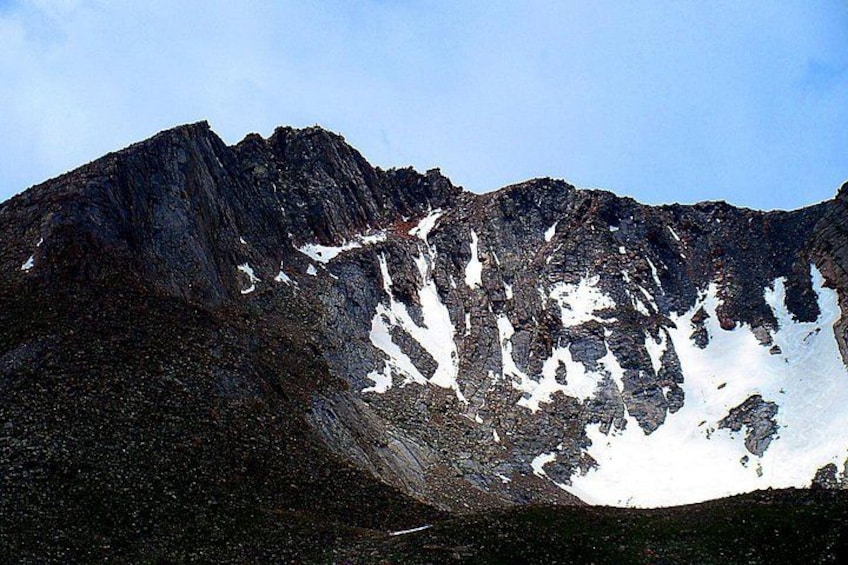 Une montagne parsemée de plaques de neige et aux reliefs rocheux. 2