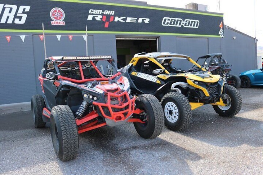 Twee offroadvoertuigen geparkeerd voor een gebouw met 'can-am RYKER' branding. 5