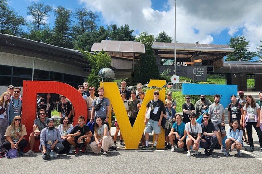 Un grupo de personas posando frente a una gran escultura con las letras 'D' y 'V'. 2
