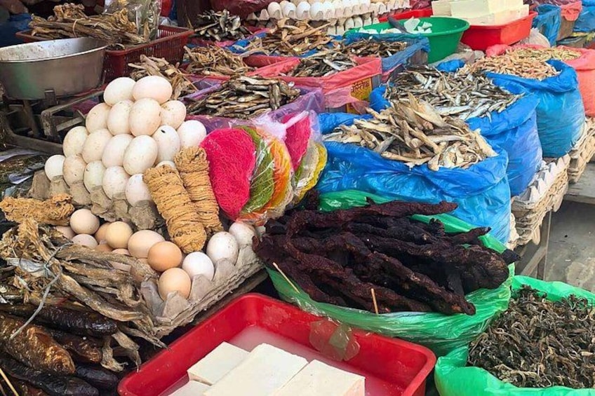 A market stall with various food items including eggs, dried fish, and vegetables. 3