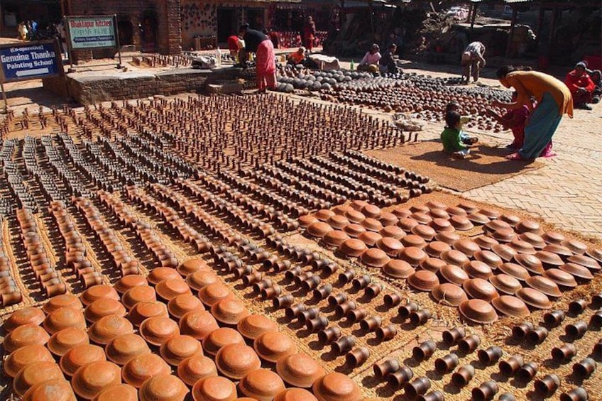 Terracotta krukker arrangeret i rækker på et teglstensbelagt område. 4