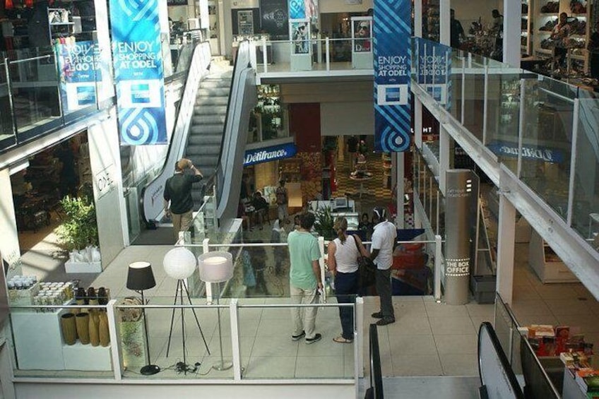 A shopping mall with escalators, glass railings, and people shopping. 2