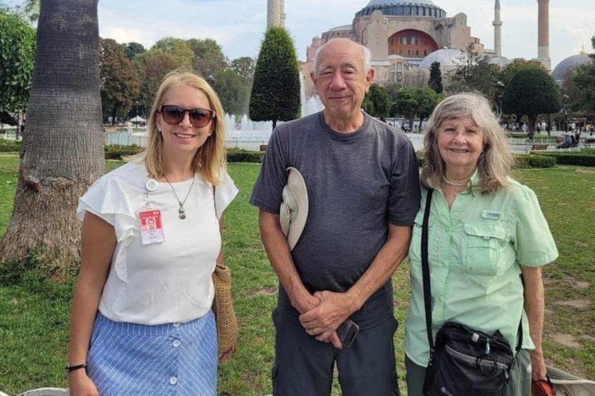 Three people standing in a park with a large building in the background. 2