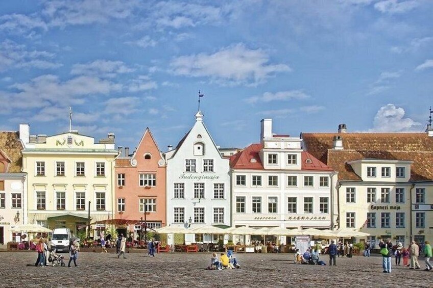 Ein historischer Stadtplatz mit bunten Gebäuden, gepflastertem Boden und Passanten. 2
