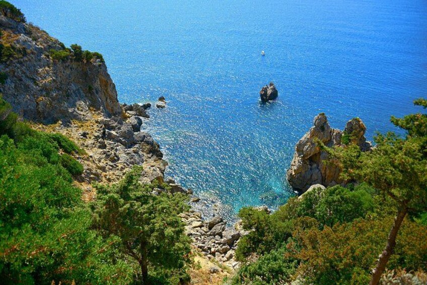 Un paisaje costero con acantilados rocosos, mar azul cristalino y abundante vegetación. 2
