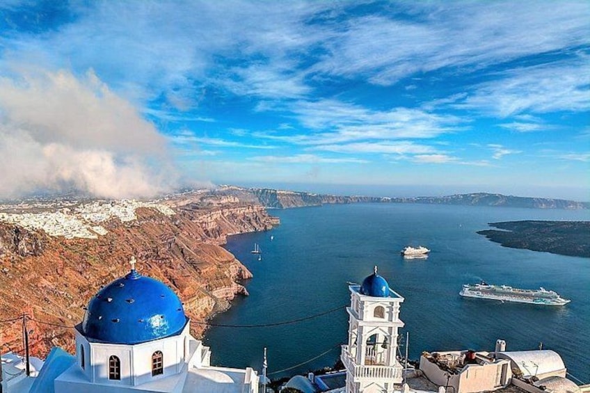 A coastal town with white buildings, a blue-domed church, and a large body of water with boats. 4