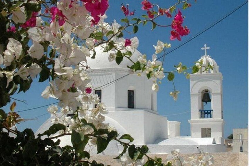 Una iglesia blanca con un campanario, rodeada de flores y follaje blanco. 3