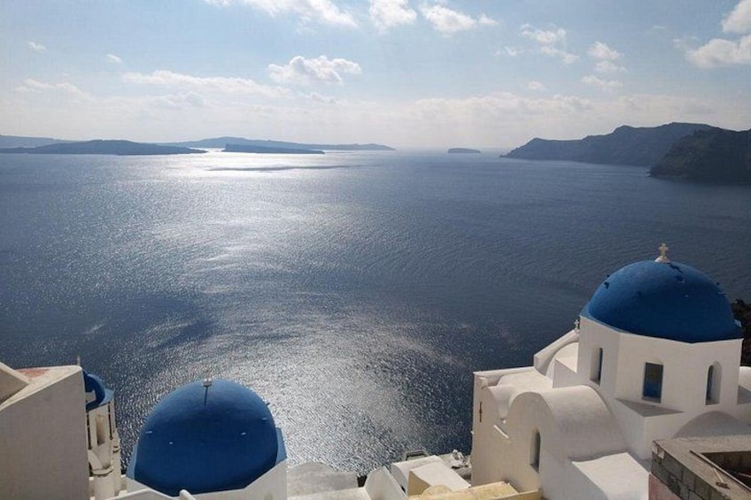 Une vue côtière avec une étendue d’eau, un ciel dégagé et des bâtiments blancs surmontés de coupoles bleues. 4