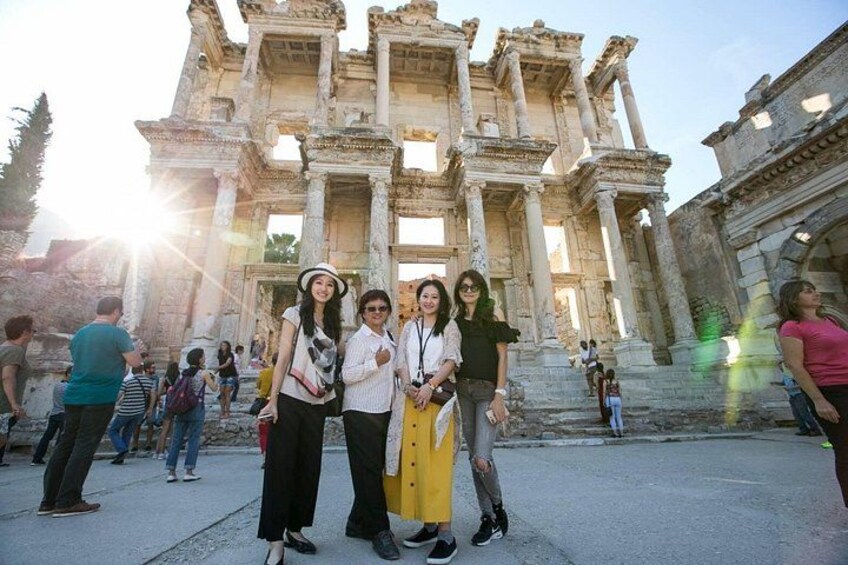 Un groupe de personnes se tient devant des ruines antiques, avec des colonnes et des arches. 1