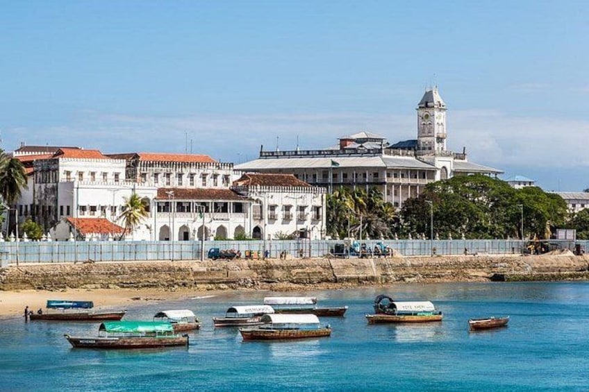 Une ville côtière qui se distingue par un imposant bâtiment blanc, un beffroi et plusieurs bateaux sur l’eau. 4