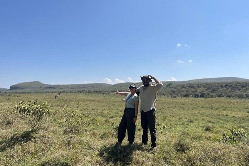 Three people standing in a grassy field with hills in the background. 4