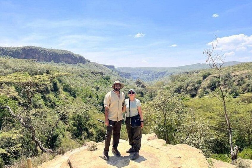 Two people standing on a rocky outcrop with a mountainous landscape in the background. 5