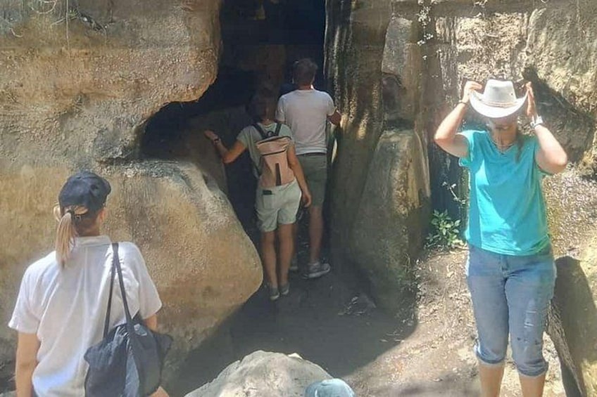 A group of people at a cave entrance with rocky walls. 2