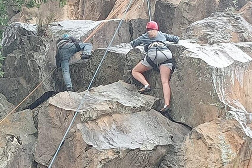 Two people rappelling down a rocky cliff. 2