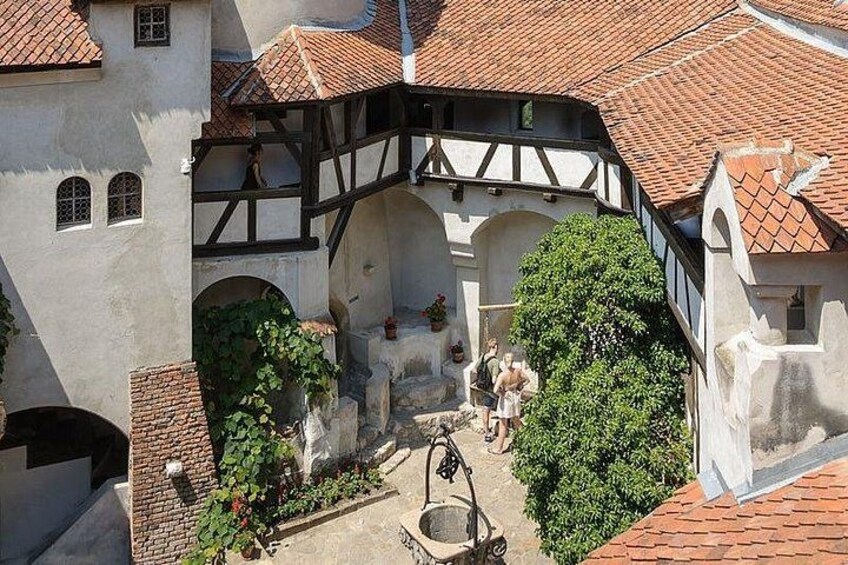 Un cortile con un edificio a graticcio, archi e una fontana. 2