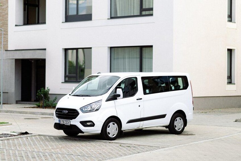 A white van parked in front of a modern building with large windows. 3