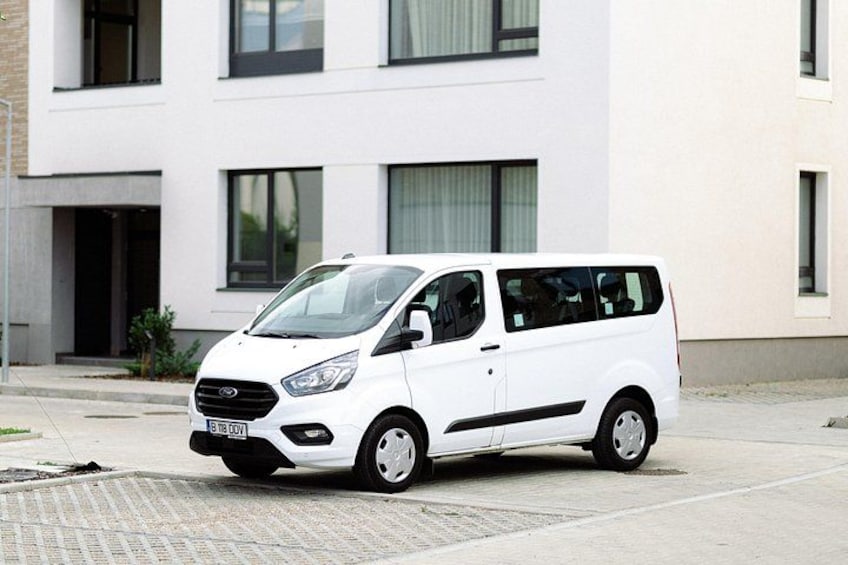 A white van parked in front of a modern building with large windows and a flat roof. 2