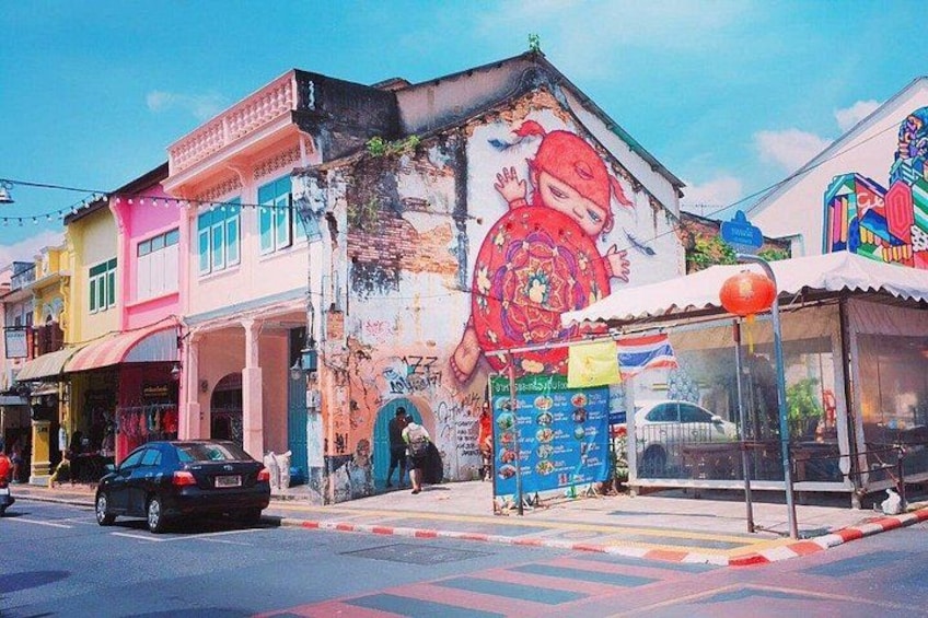 A street with colorful buildings, a mural, and a bus stop. 2