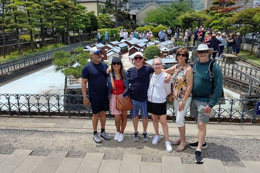 A group of people standing on a paved area with a canal and a bridge in the background. 4
