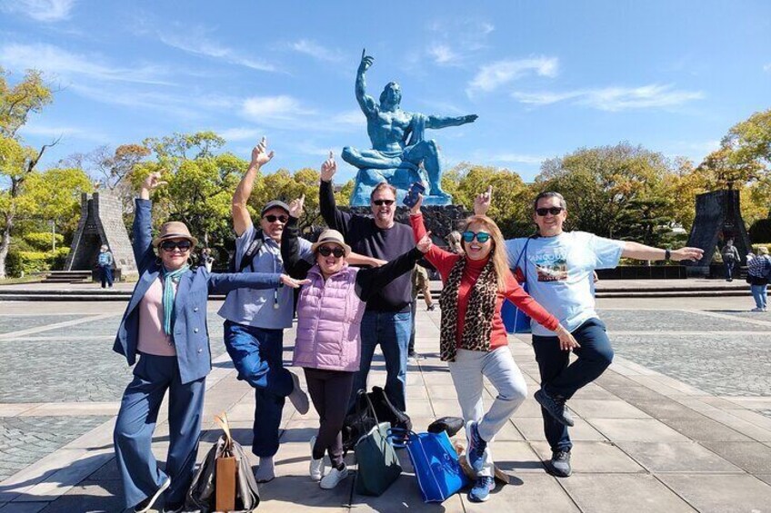 En gruppe mennesker poserer foran en statue i en park. 1