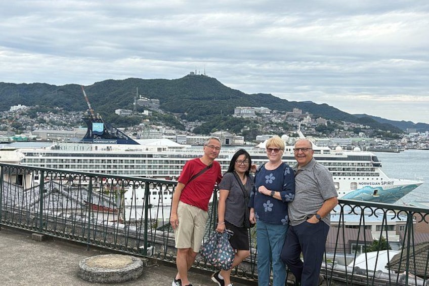 A group of people standing on a bridge with a cruise ship in the background. 2