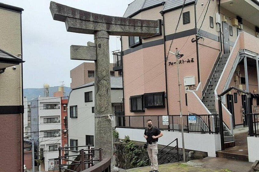 A stone torii gate, a residential building, and a person standing in front of the gate. 5