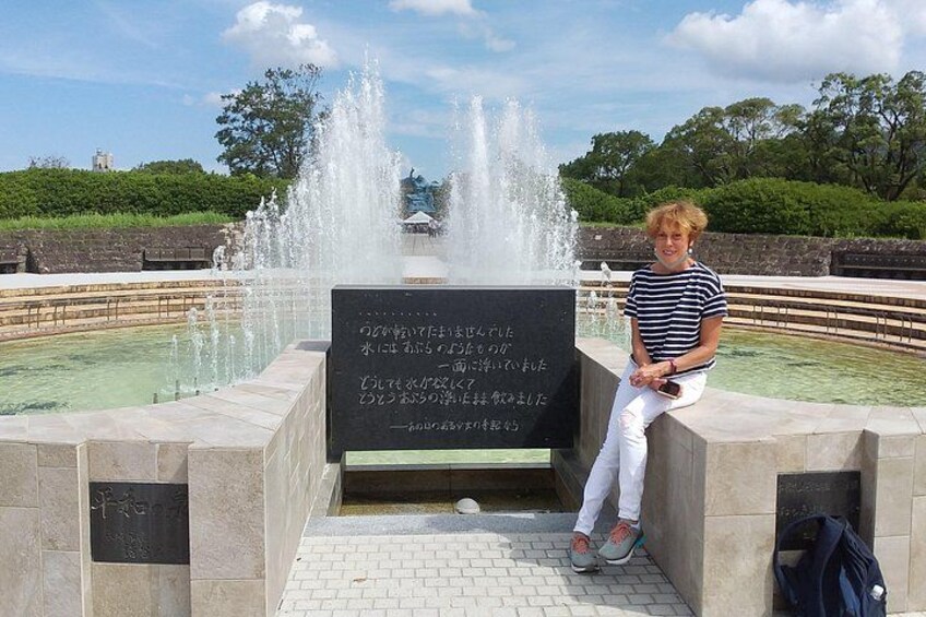 A person sitting by a fountain with a sign in front of them. 3