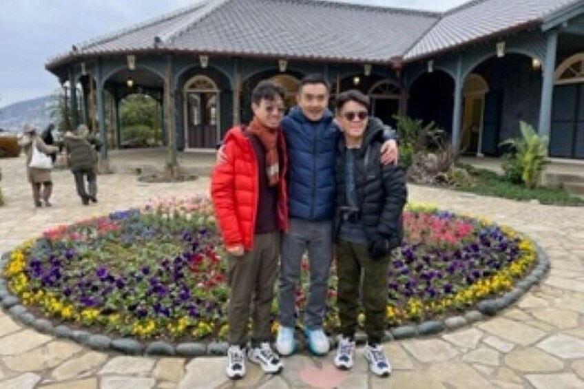Three people standing in front of a building with a garden. 4