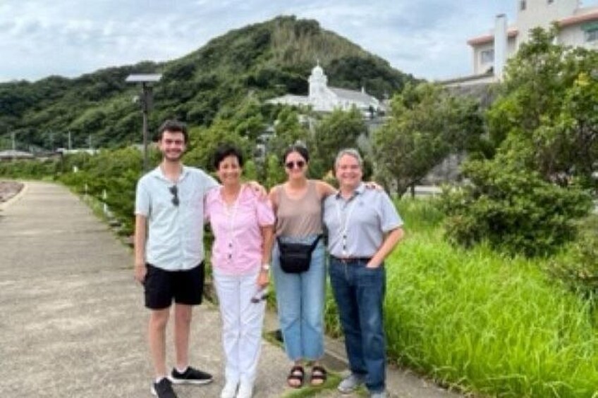 A group of people standing on a pathway with a hill and a white building in the background. 3