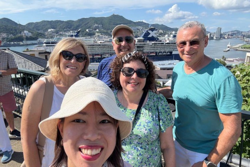 A group of people standing on a balcony overlooking a harbor with boats and a cruise ship. 2