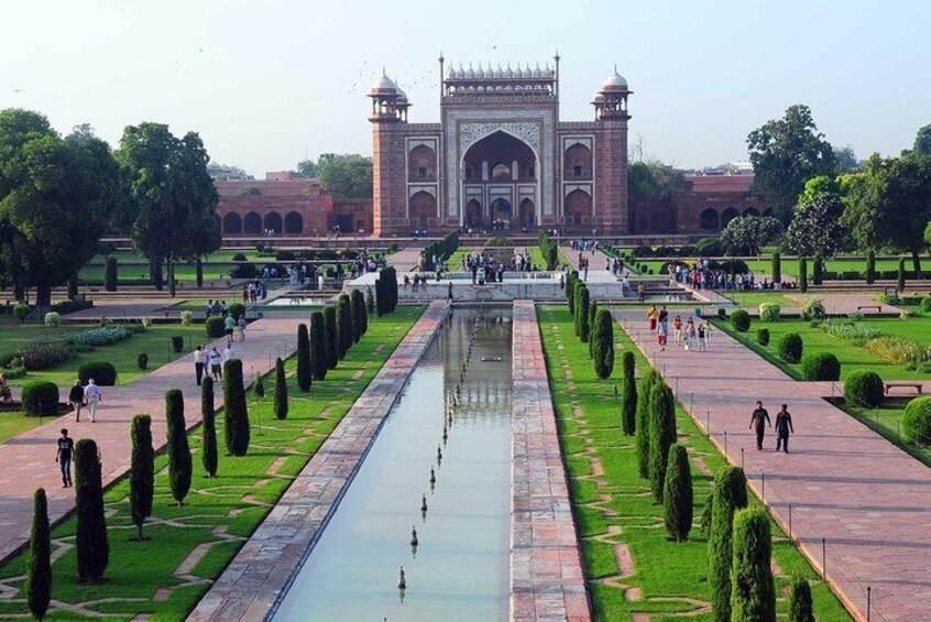 El Taj Mahal reflejado en el agua, rodeado de jardines cuidados y senderos. 4