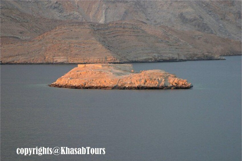 A large rock formation in a body of water with a mountainous background. 5