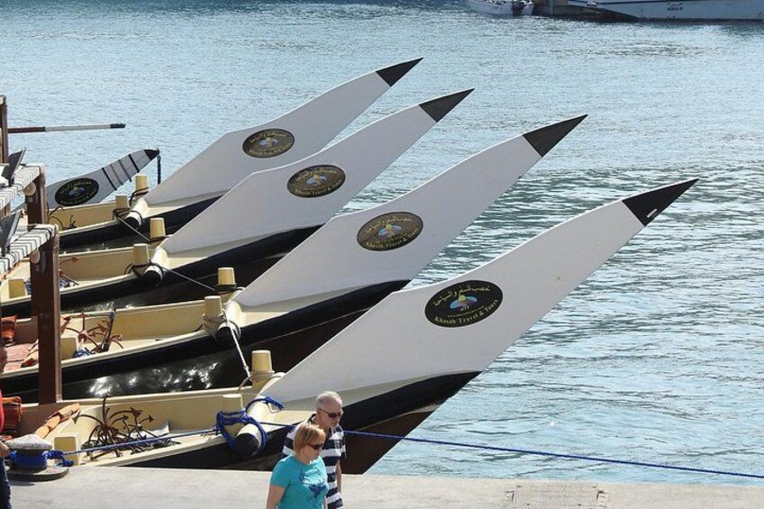 A row of canoes with logos on their sides, docked at a marina. 2