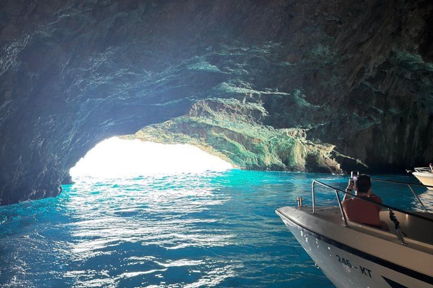 Un bote en la abertura de una cueva natural con agua azul cristalina. 2