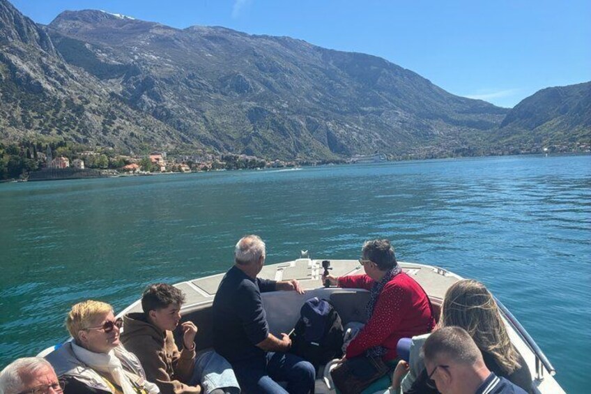 A group of people on a boat on a lake with mountains in the background. 2