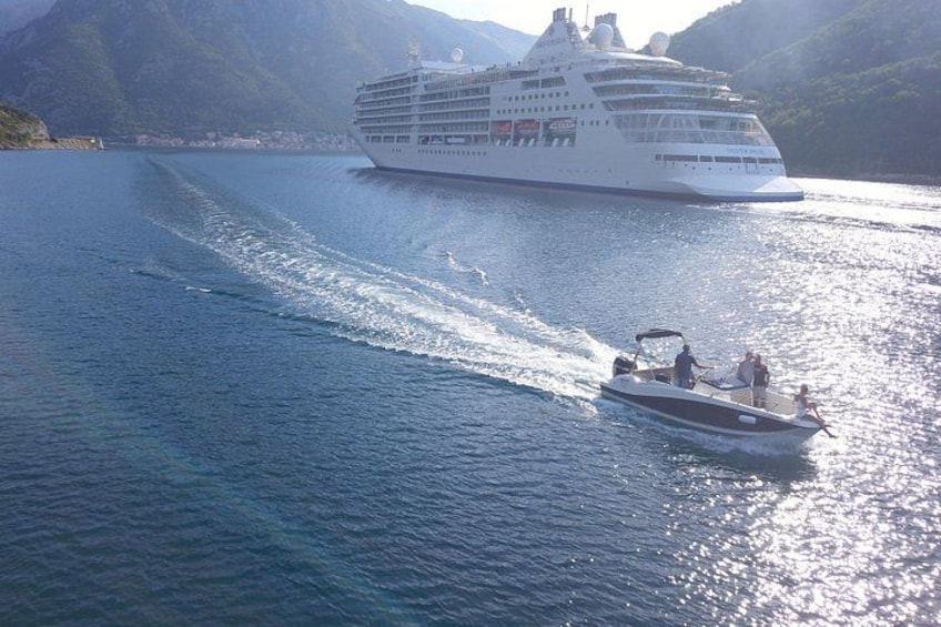 Un crucero y una embarcación más pequeña en aguas tranquilas, con montañas al fondo. 4