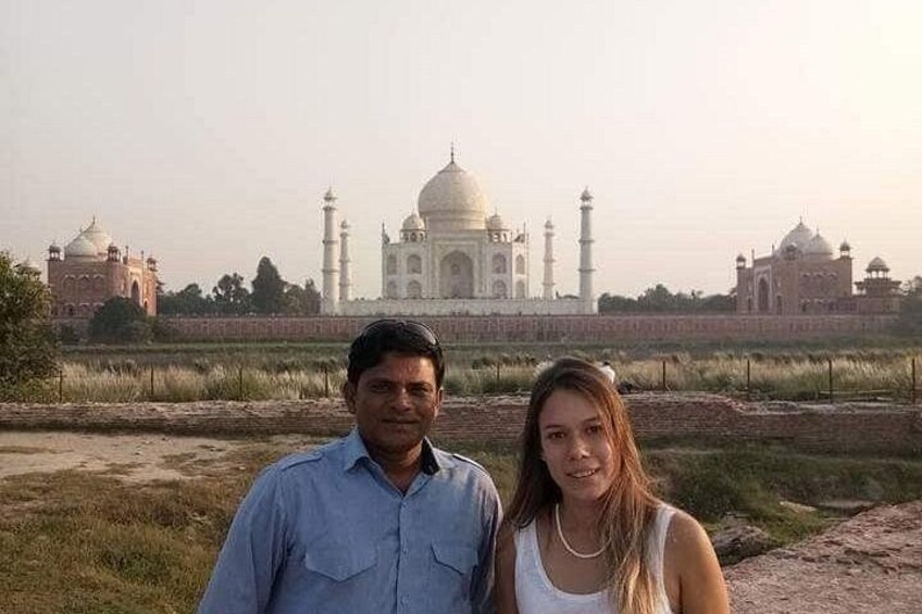 Dos personas de pie frente al Taj Mahal, con la estructura al fondo. 1