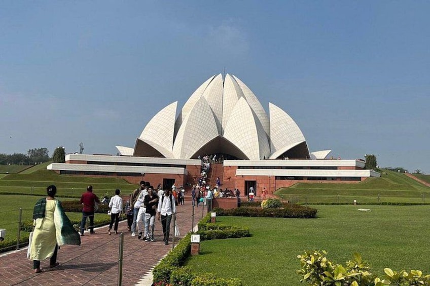A large white lotus-shaped building with people walking towards it. 1
