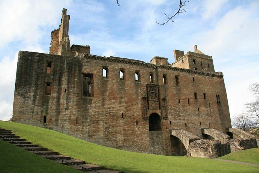 Un grand château historique, avec une colline verdoyante au premier plan. 1