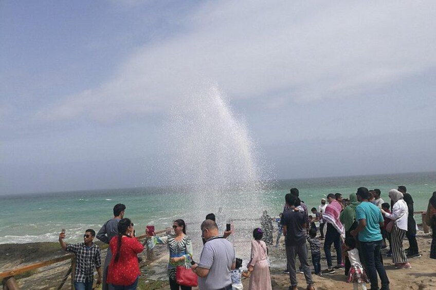 Un grupo de personas en la playa junto a una fuente que rocía agua. 1