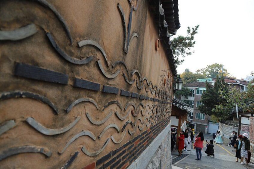 A traditional building with carved patterns, a staircase, and people walking. 3