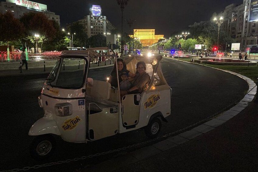 Een tuk-tuk met verlichte lampen, geparkeerd op een gebogen weg in de nacht. 1