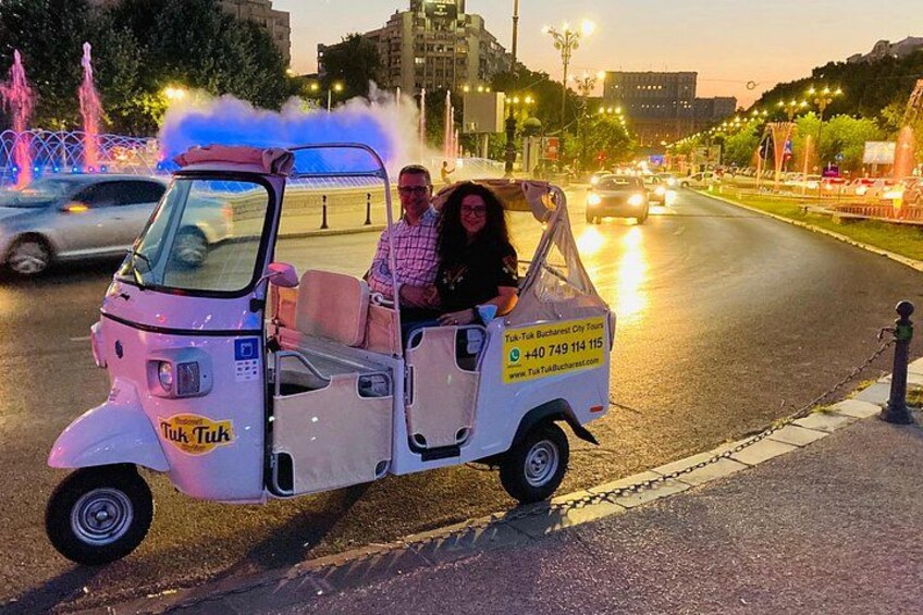 Een tuk-tuk op een stadsweg, met een persoon achterin. 5
