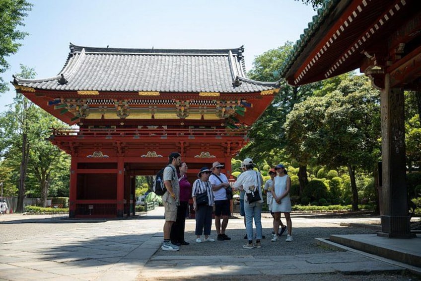A traditional red gate with intricate designs, surrounded by lush greenery and a clear sky. 5