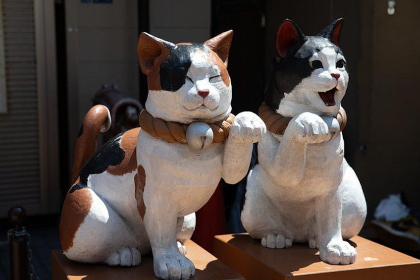 Two cat sculptures with collars sitting on a wooden platform. 4